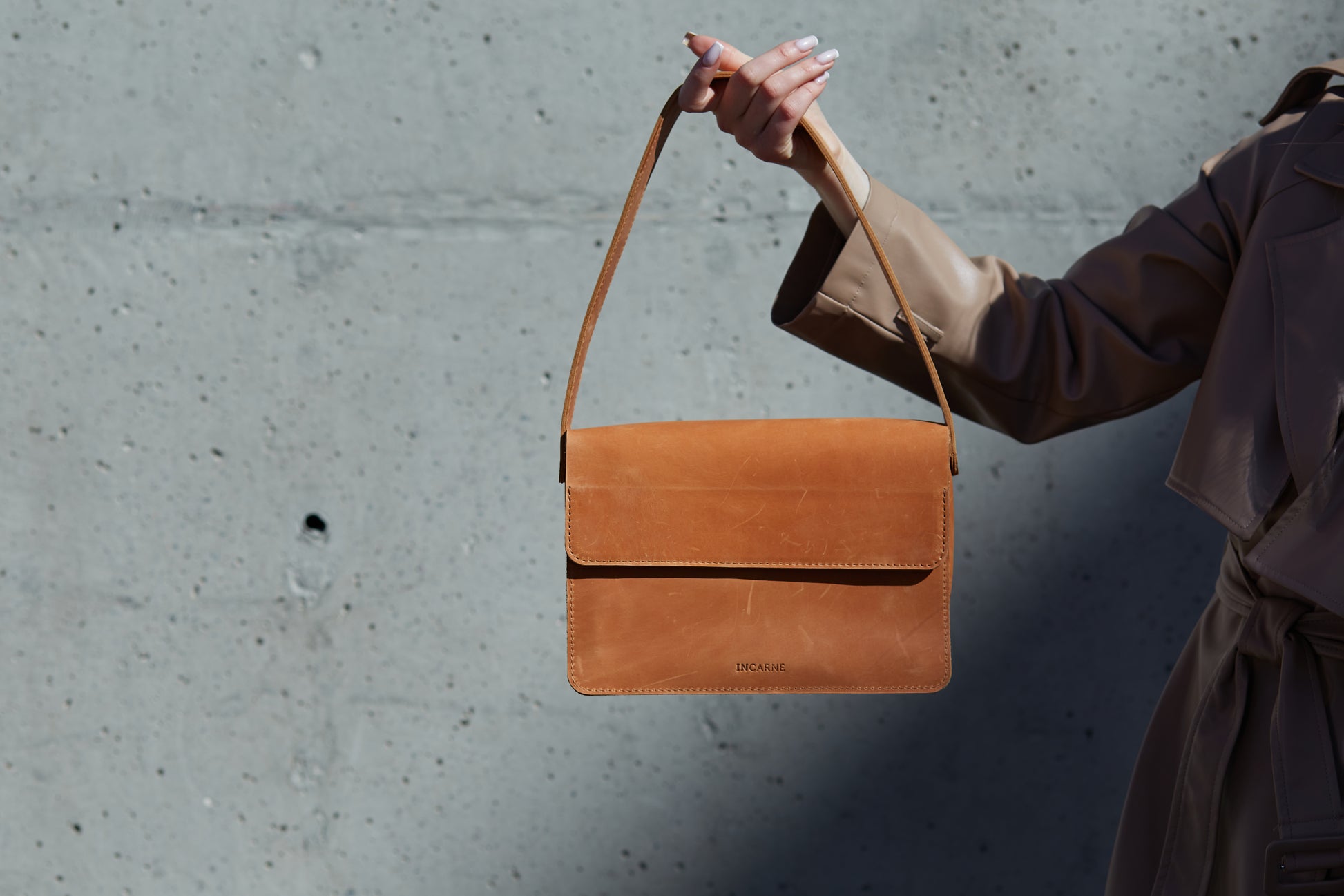 woman in a leather coat is wearing a leather bag for women in cognac color