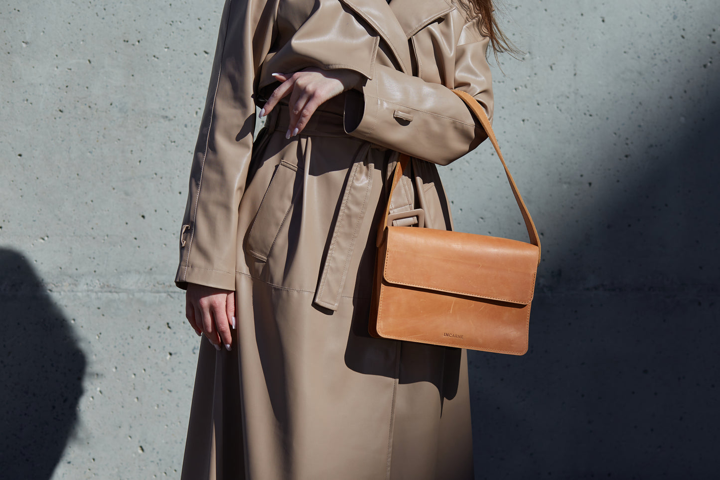 woman in a leather coat is wearing a leather bag for women in cognac color