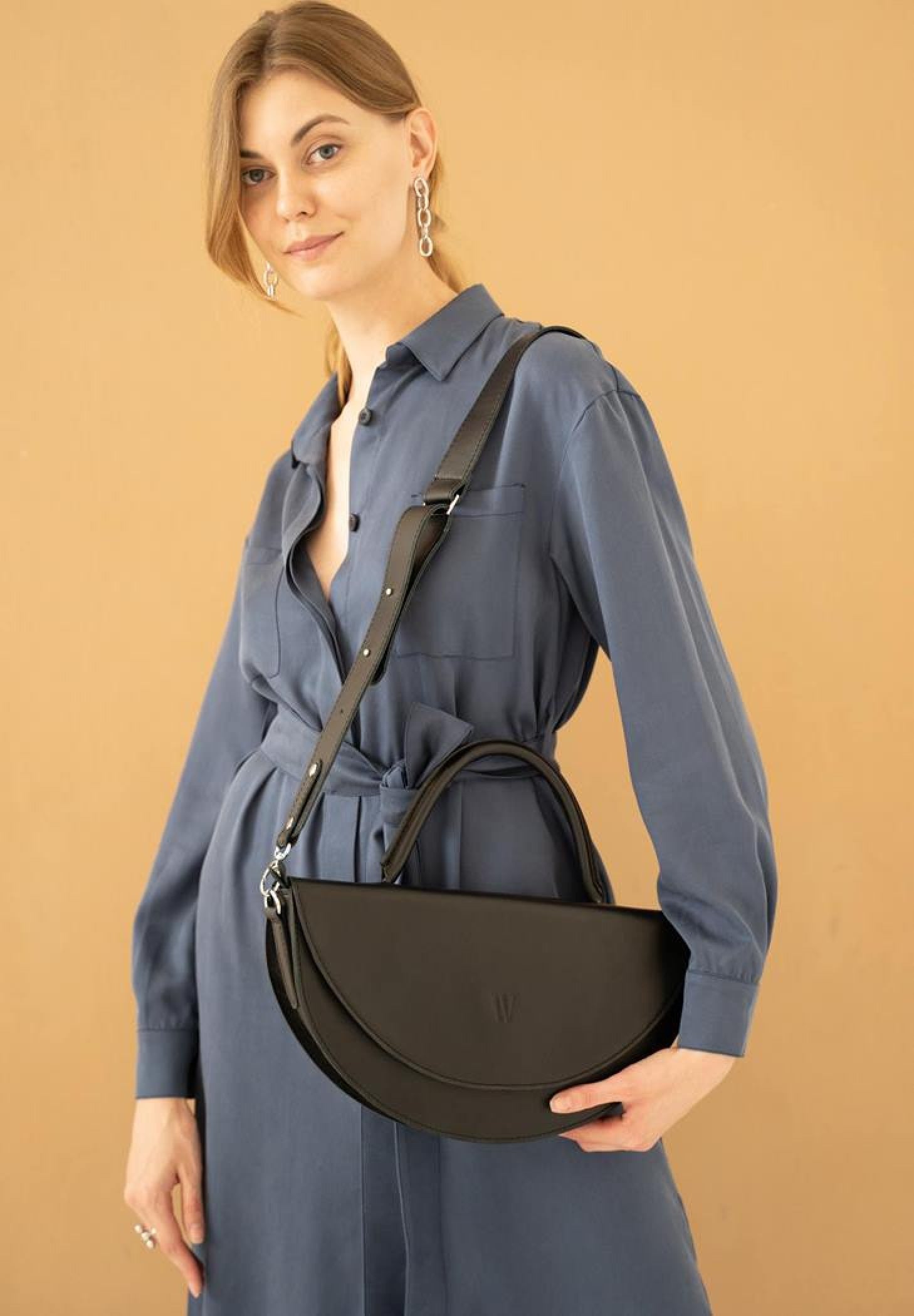 woman in blue blouse wearing black leather bag
