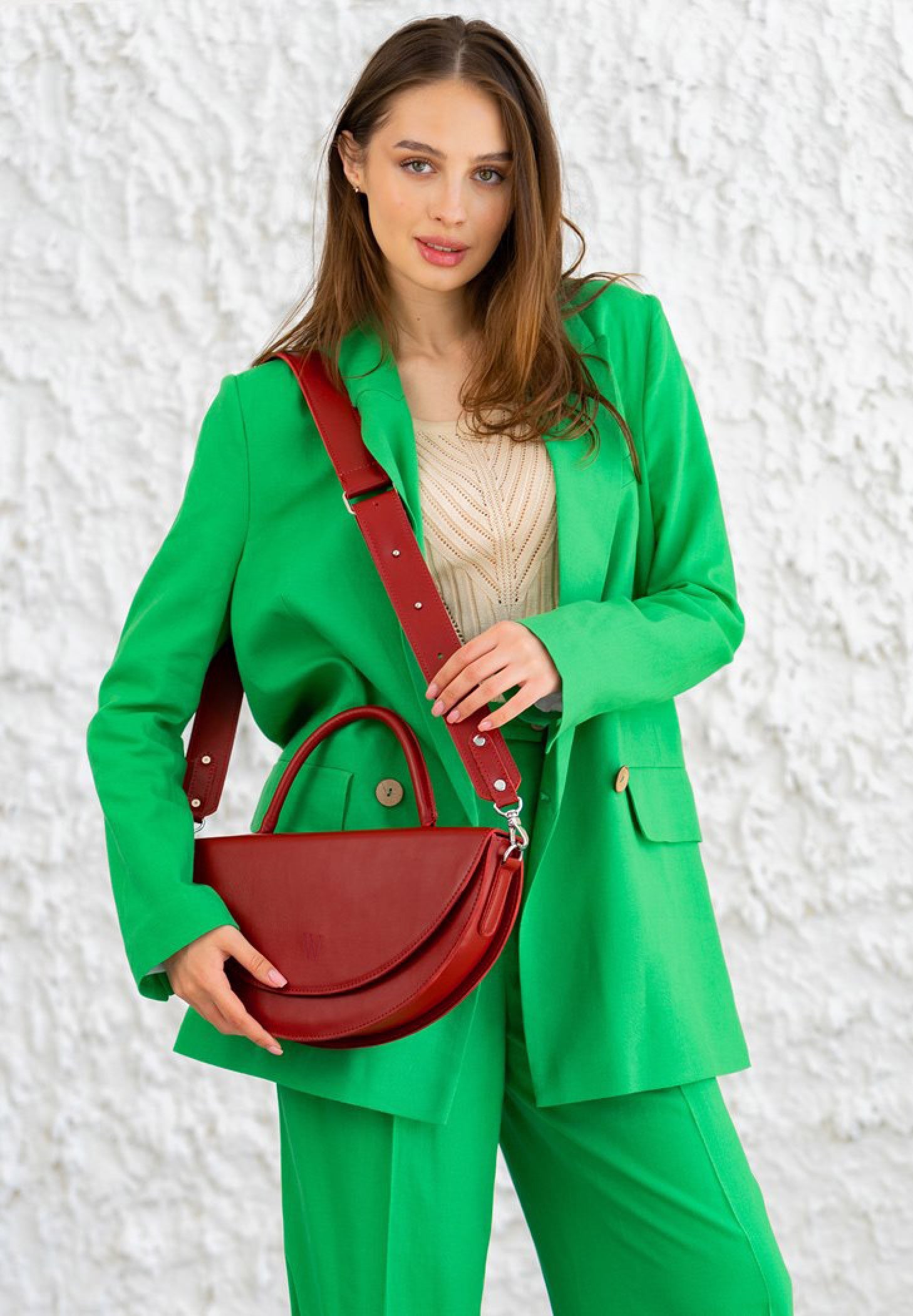 woman in a green outfit holding red leather bag