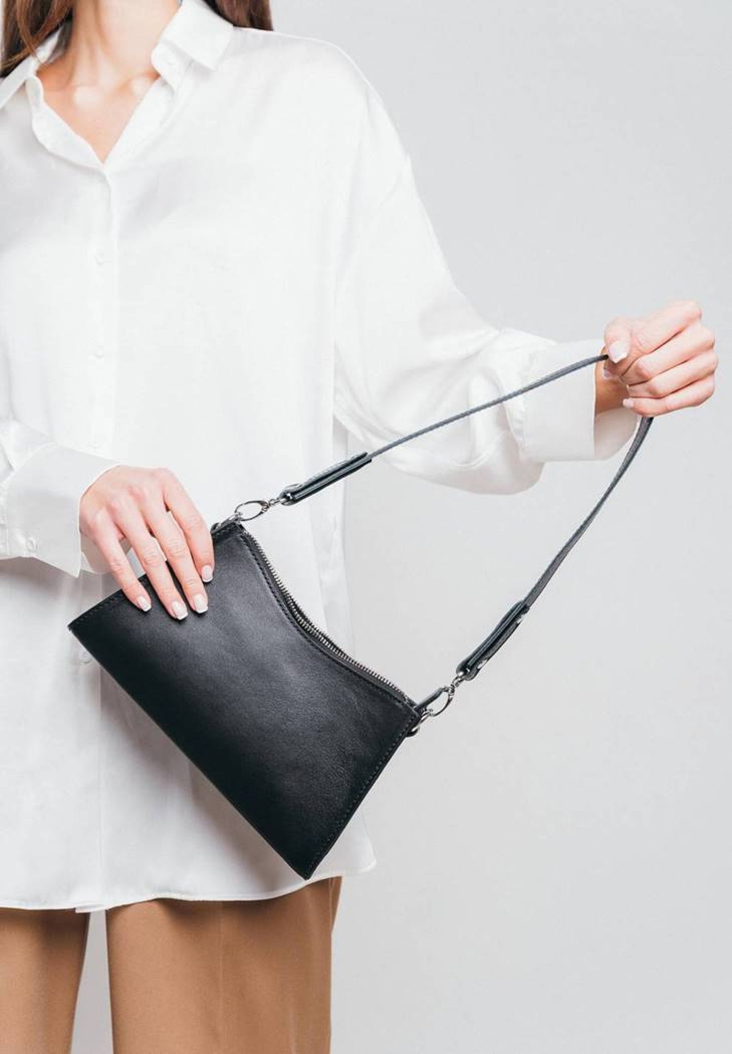 woman is holding a black leather bag for women