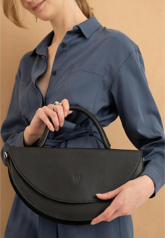woman in blue blouse wearing black leather bag