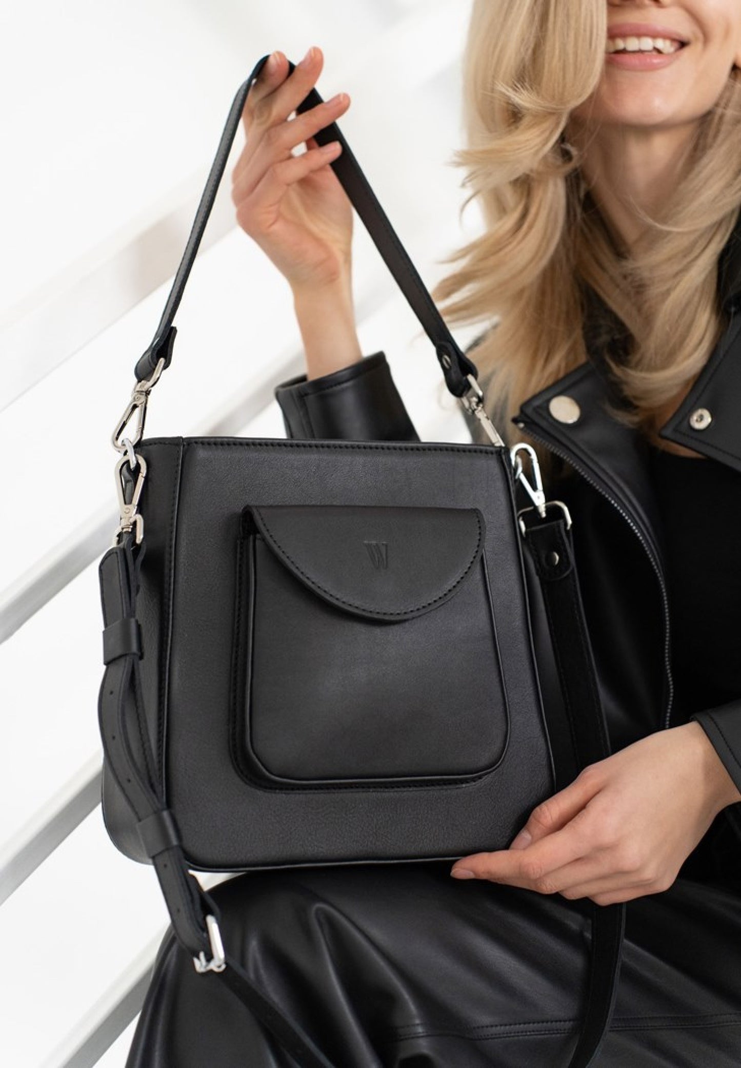 beautiful woman with blond hair is holding a black exquisite leather bag for women